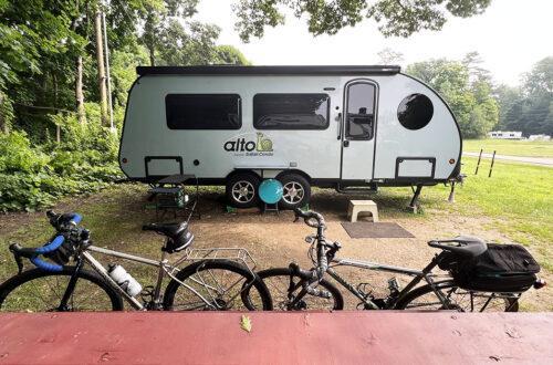 Camper parked under trees with bicycles in the foreground