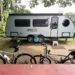 Camper parked under trees with bicycles in the foreground